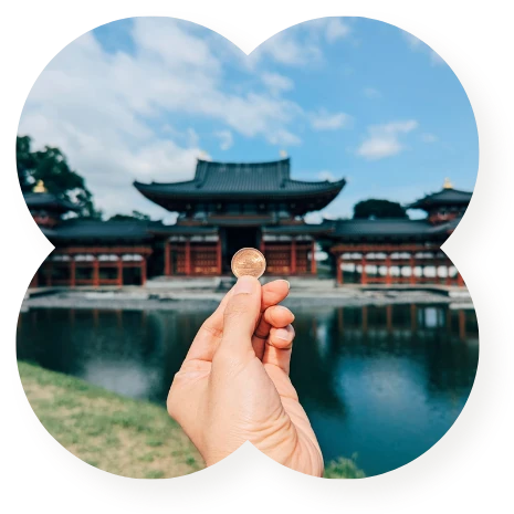 A traveler holding a coin in front of a traditional Japanese building